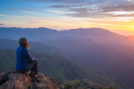 Happy celebrating winning success woman at sunset or sunrise standing elated with arms raised up...