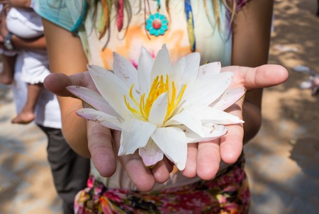 woman holding a white lotus flower on her handsの写真素材