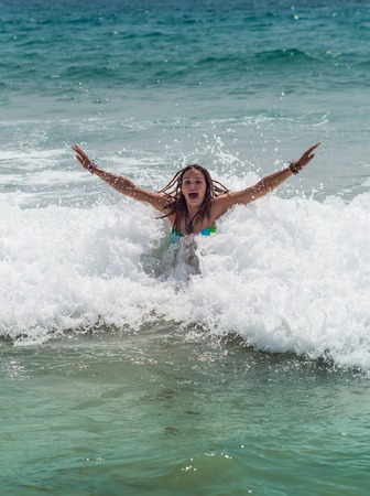 girl laughing and crying in the spray of waves at sea on a sunny  dayの写真素材