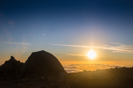 Tourist stand near tent and lake shore and looking at the beautiful  sunsetの写真素材