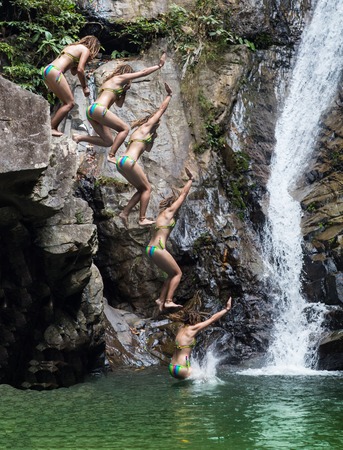 jumping into a waterfall with a large rock in the jungleの写真素材
