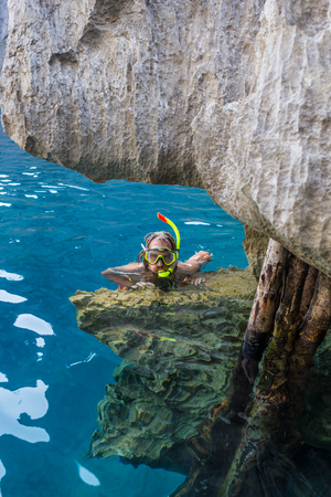 Young man snorkeling in clear shallow tropical sea over coral reefsの写真素材