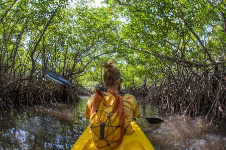 Young lady paddling hard the sea kayak with lots of splashesの写真素材