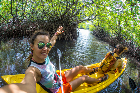 Young lady paddling hard the sea kayak with lots of splashesの写真素材