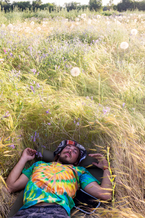 Portrait of a young happy man relaxing on the grass with his hands under the headの写真素材