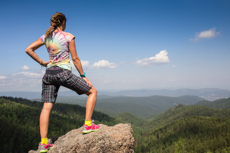 Young woman sitting on a rock with backpack and looking to the horizonの写真素材