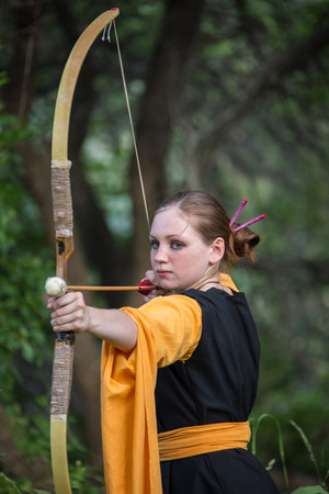 Beautiful woman drawing a bow in the forestの写真素材