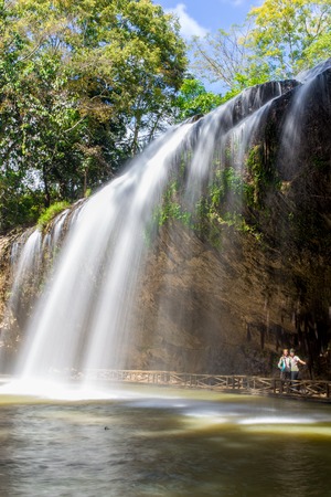 Young couple in love walking in the woods with waterfall on backgroundの写真素材