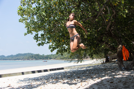 teenage girl balancing on slackline with sky view on the beach.の写真素材