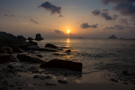 Beautiful sunset view of surf at beach with golden glow of sun reflecting off of water.の写真素材