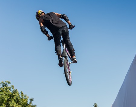 KAZAKHSTAN ALMATY - AUGUST 28, 2016: Urban extreme competition, where the city athletes compete in the disciplines: skateboard, roller skates, BMX. Bmx stunt performed at the top of a mini ramp on a skateparkのeditorial素材
