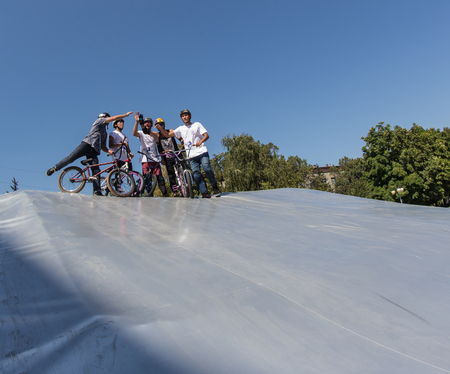 KAZAKHSTAN ALMATY - AUGUST 28, 2016: Urban extreme competition, where the city athletes compete in the disciplines: skateboard, roller skates, BMX. Bmx stunt performed at the top of a mini ramp on a skatepark.Winners team on the mountain top. Sport and acのeditorial素材