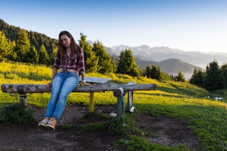 Young woman sitting on a rock with backpack and looking to the horizonの写真素材