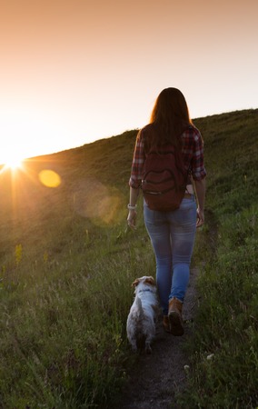 Young woman with dog on a sunny day hiking in high mountains.の写真素材