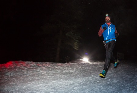 ALMATY, KAZAKHSTAN - 18 FEBRUARY 2017: Night competitions in the foothills of the city of Almaty, in the Trailrunning and Skyship discipline, which is called TunRun winter edition. Man running in the mountains at nightのeditorial素材