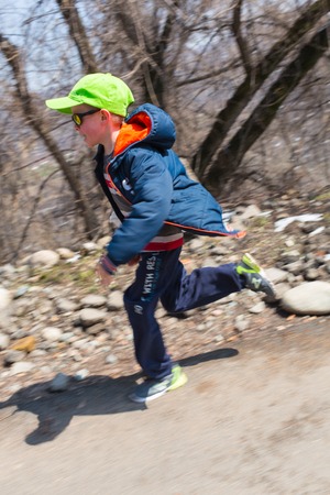 ALMATY, KAZAKHSTAN - APRIL 09, 2017: Amateur competitions - Mountain half-marathon, in the foothills of Almaty, on the Yunat lakes. happy little boy go home from schoolのeditorial素材