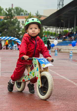 KAZAKHSTAN, ALMATY - JUNE 11, 2017: Childrens cycling competitions Tour de kids. Children aged 2 to 7 years compete in the stadium and receive prizes. A little boy rides a bike and competes to become a winner.のeditorial素材