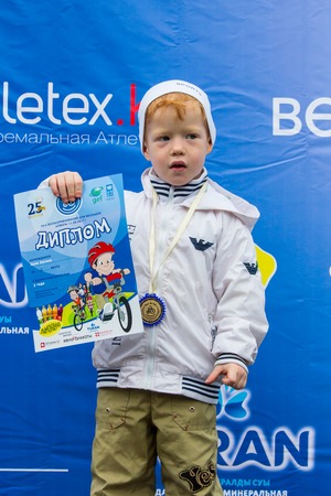 KAZAKHSTAN, ALMATY - JUNE 11, 2017: Childrens cycling competitions Tour de kids. Children aged 2 to 7 years compete in the stadium and receive prizes. Excited boy and girls with medalsのeditorial素材
