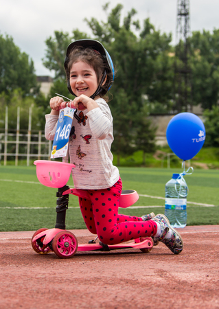 KAZAKHSTAN, ALMATY - JUNE 11, 2017: Childrens cycling competitions Tour de kids. Children aged 2 to 7 years compete in the stadium and receive prizes. The girl on a bicycle rides on a sports stadium and competes to win.のeditorial素材
