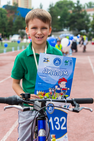 KAZAKHSTAN, ALMATY - JUNE 11, 2017: Childrens cycling competitions Tour de kids. Children aged 2 to 7 years compete in the stadium and receive prizes. Excited boy and girls with medalsのeditorial素材