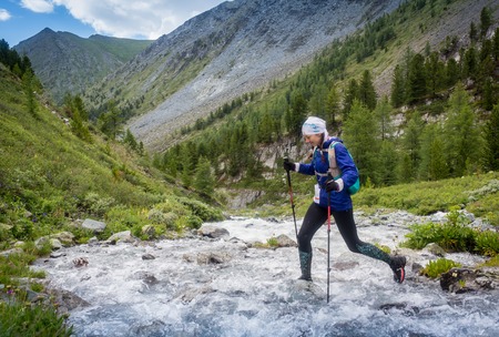 The girl runs along the mountain river, participate in competitions in the mountains of Altai, Russia.の写真素材