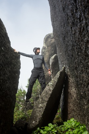 male rock climber. rock climber climbs on a black rocky wall on the ocean bank in Iceland, Kirkjufjara beach. man makes hard move without ropeの写真素材