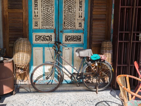 Old bicycle leaning against grungy barn in Thailandの写真素材