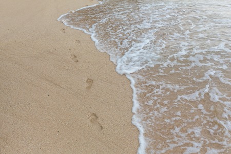 beach, wave and footprints at sunset timeの写真素材