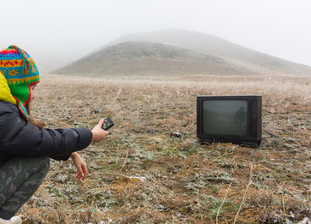 Girl on the nature lying on the ground and watching an old TVの写真素材