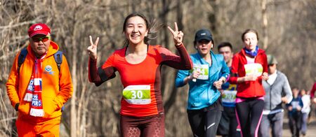 ALMATY KAZAKHSTAN - MARCH 16 2019: a dense group of unidentified men and women runs through a grove...