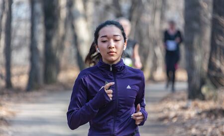 ALMATY, KAZAKHSTAN - March 16, 2019: a beautiful young unidentified girl runs through the woods...