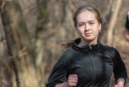 ALMATY, KAZAKHSTAN - March 16, 2019: a beautiful young unidentified girl runs through the woods...