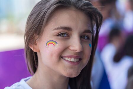 ALMATY, KAZAKHSTAN - JUNE 10, 2018: Unidentified girl makeup artist makes a bright carnival face painting to the festival participants at the Yarkokros party near the Almaty Arena stadium on June 10, Sunday in the city of Almaty.のeditorial素材