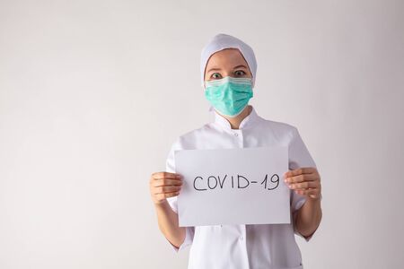 Girl doctor in a mask holds a tablet in his hands - with coronavirus.の写真素材