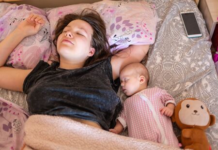 Young mother and her baby, sleeping in bed