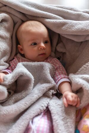 pretty smiling baby girl and toy rabbit lying in light background