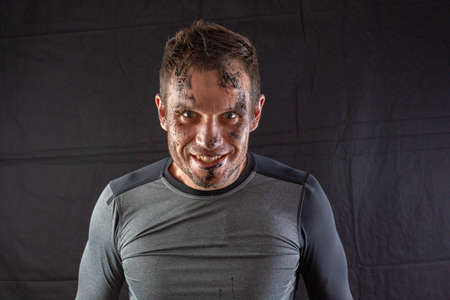 Handsome shirtless fitness man in gray shorts, smiling and posing against dark black background. Mild retouch, studio lighting.の写真素材