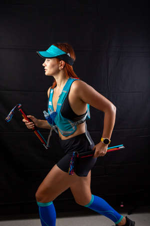 Girl marathon runner in full blue uniform runs in the studio on a black backgroundの写真素材