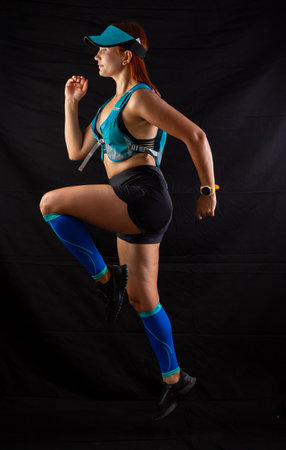 girl in blue jogging uniform runs in the studio on a black background