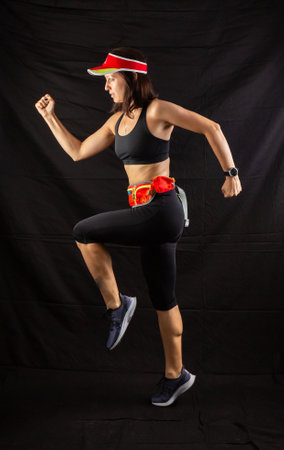 girl in red jogging uniform runs in the studio on a black backgroundの写真素材