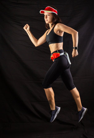 girl in red jogging uniform runs in the studio on a black backgroundの写真素材