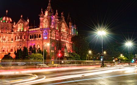 Photo for Very famous Victoria Terminus of Mumbai,aka Chhatrapati Shivaji Maharaj Terminus, during night with fast moving traffic trails and street light glares. A UNESCO World Heritage and a local Rly. Station - Royalty Free Image