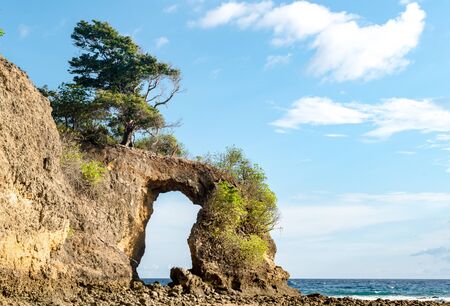 Geological formation known as Rock Arch at Neil island, looks like natural bridge or a natural gate, formed off constant erosion; with calm sea and clear blue sky in background with visible horizon.の写真素材