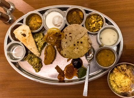 Food plate - full of Indian Cuisine, consisting variety of traditional dishes from all over India on a wooden table in background. An Indian Delicacy, it is healthy, spicy and epicure treatの写真素材