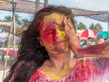 Amazing candid photo of young girl playing and enjoying Holi, festival of colors in India. Applying...