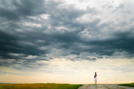 Girl looking at cloudy sky from bluffの写真素材