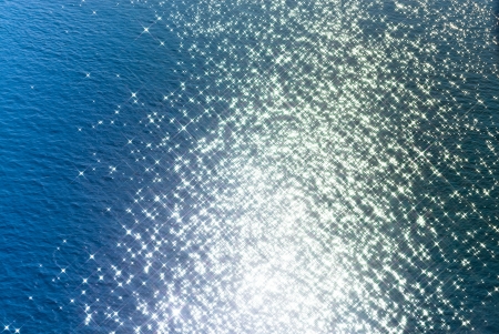Sunlight reflections on water waves through a star filterの写真素材