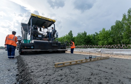 MOSCOW - MAY 16: Road workers pour asphalt with a modern paver on May 16, 2013 in Moscow.