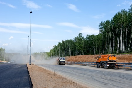 Street sweepers with clouds of dust at the road construction