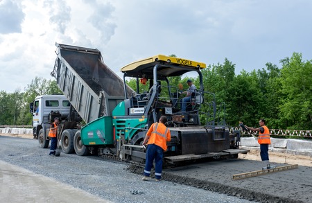 MOSCOW - MAY 16: Road workers do they job with a modern paver on May 16, 2013 in Moscow.